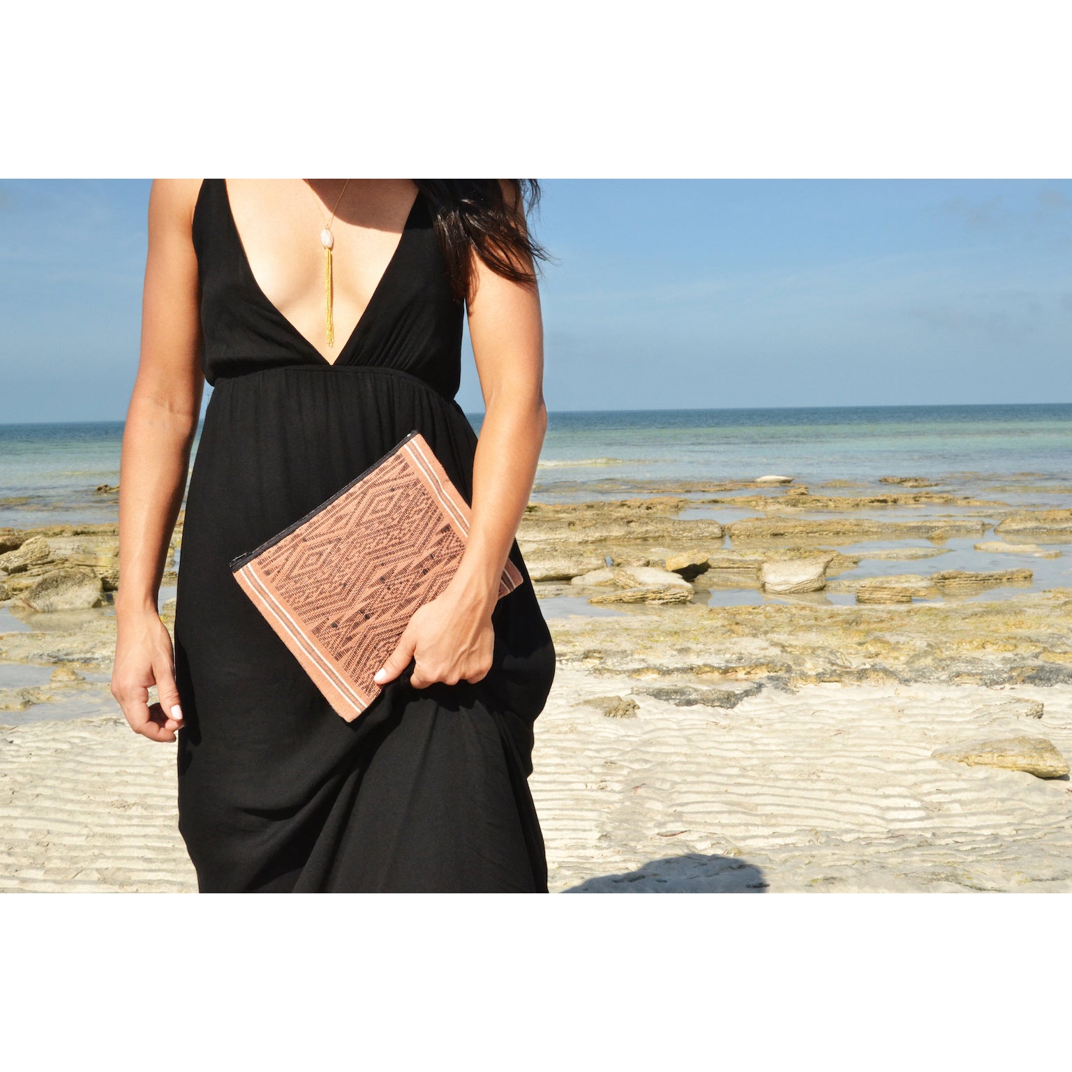 woman walking on beach holding slate and salt Sierra clutch