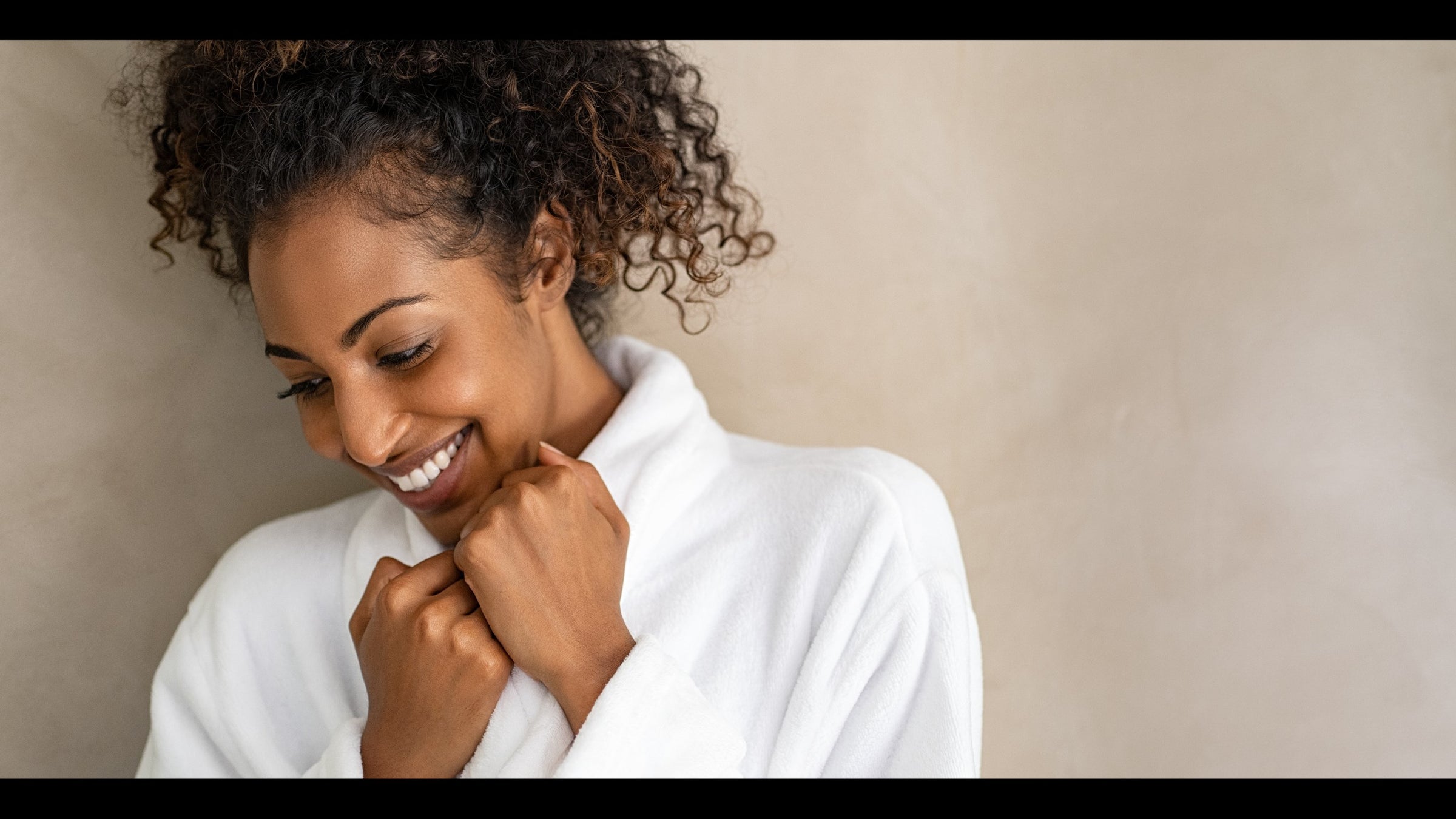 beautiful black woman smiling and wrapped in a white robe 