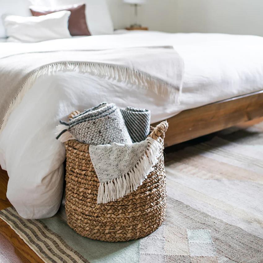 slate and salt alpaca throws in a natural woven basket at the foot of a bed